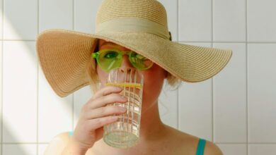 Femeie cu palarie si ochelari de soare care bea apa